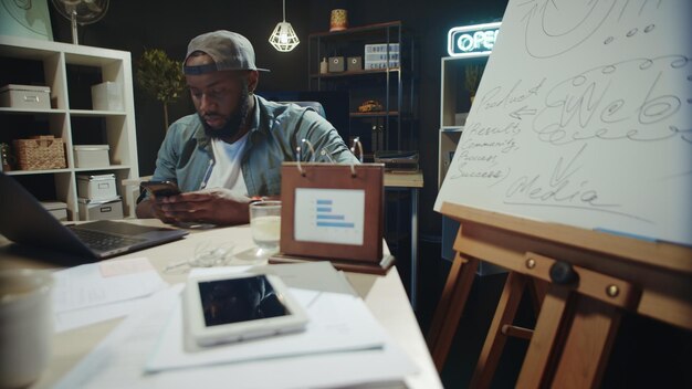 satisfied-afro-business-man-reading-message-mobile-phone-modern-office-busy-african-american-guy-checking-phone-hipster-coworking-smiling-african-man-having-break-working-space_723208-18564.jpg
